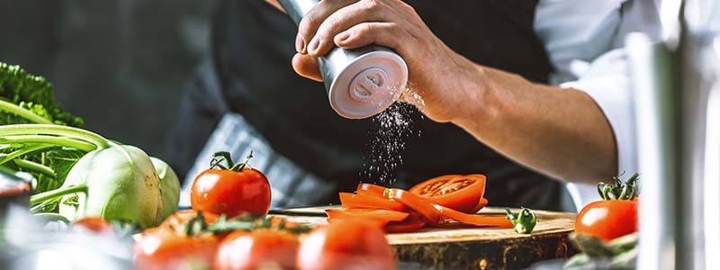 Koch beim würzen von Tomaten